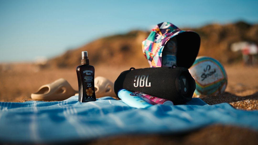 Altavoz portátil junto a objetos de playa sobre una toalla